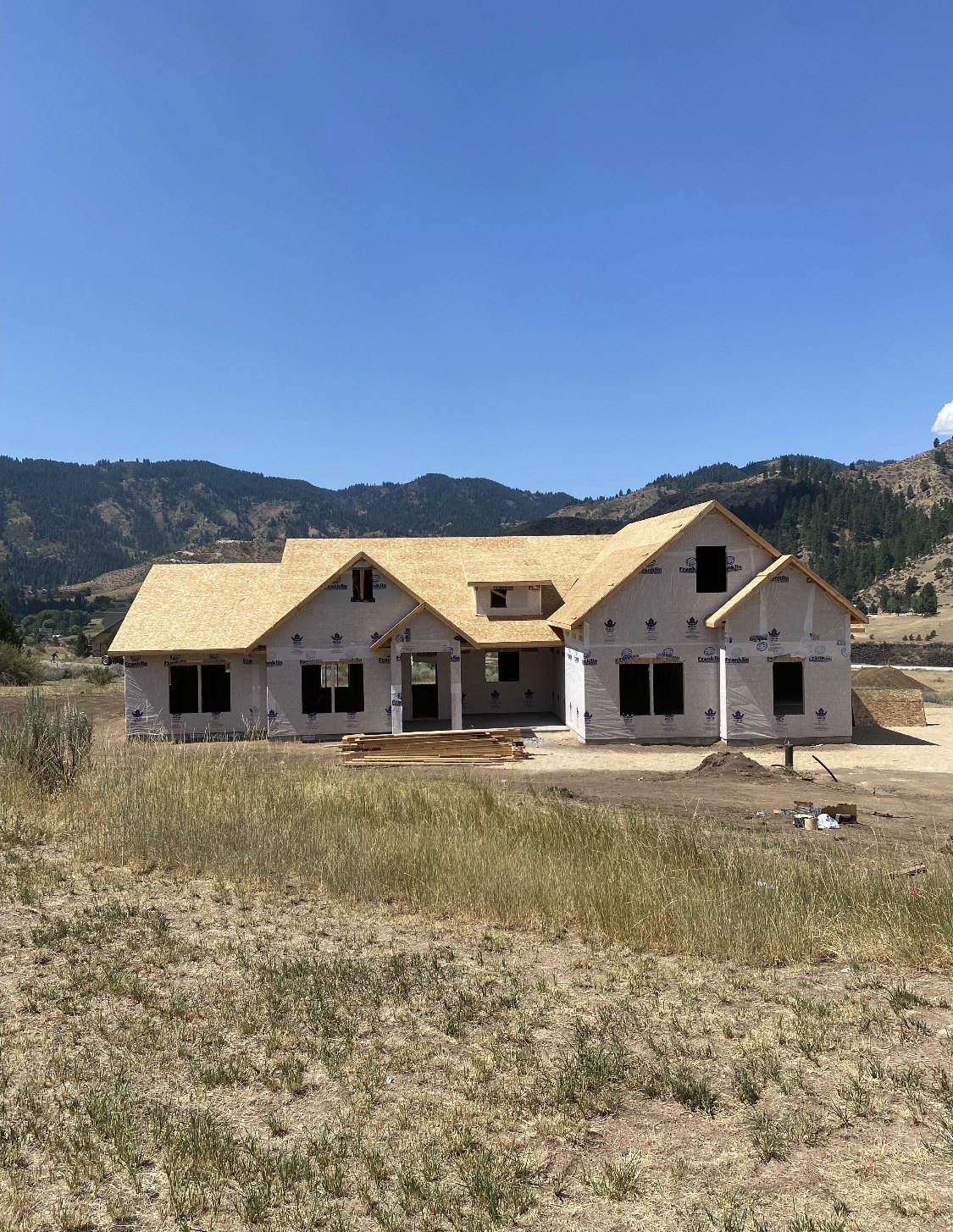 Home under construction with roof sheathing against a backdrop of Idaho hills