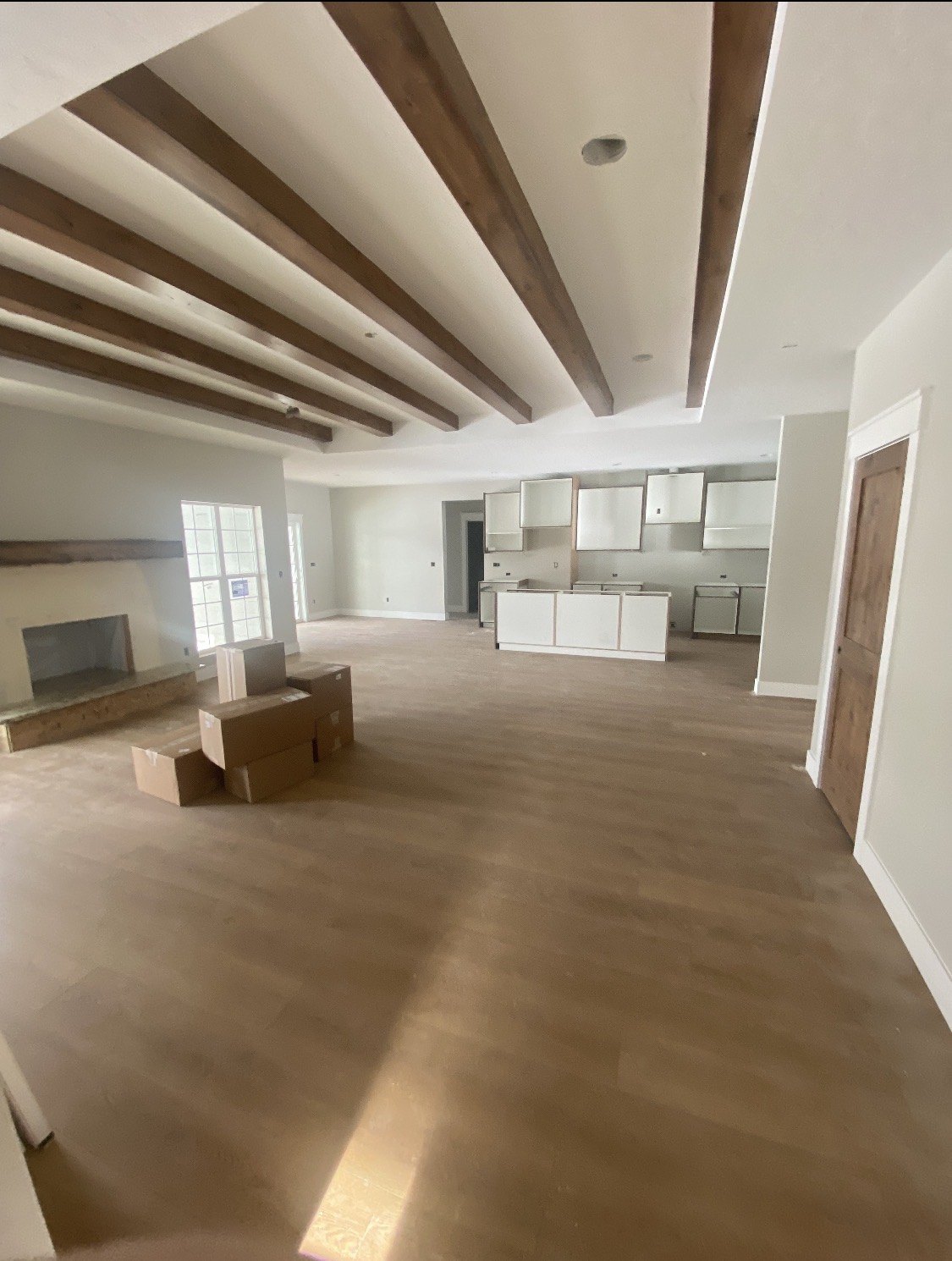 Open living area with wood ceiling beams and a white kitchen