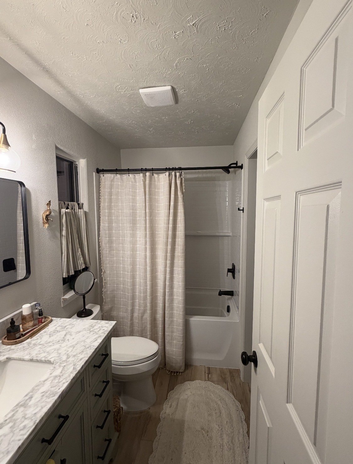 Bathroom with a long vanity, pale cabinetry, and a tub with shower curtain